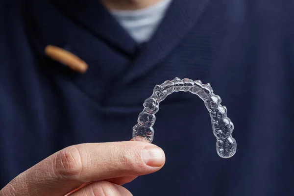man-holding-one-transparent-aligner man-holding-one-transparent-aligner
