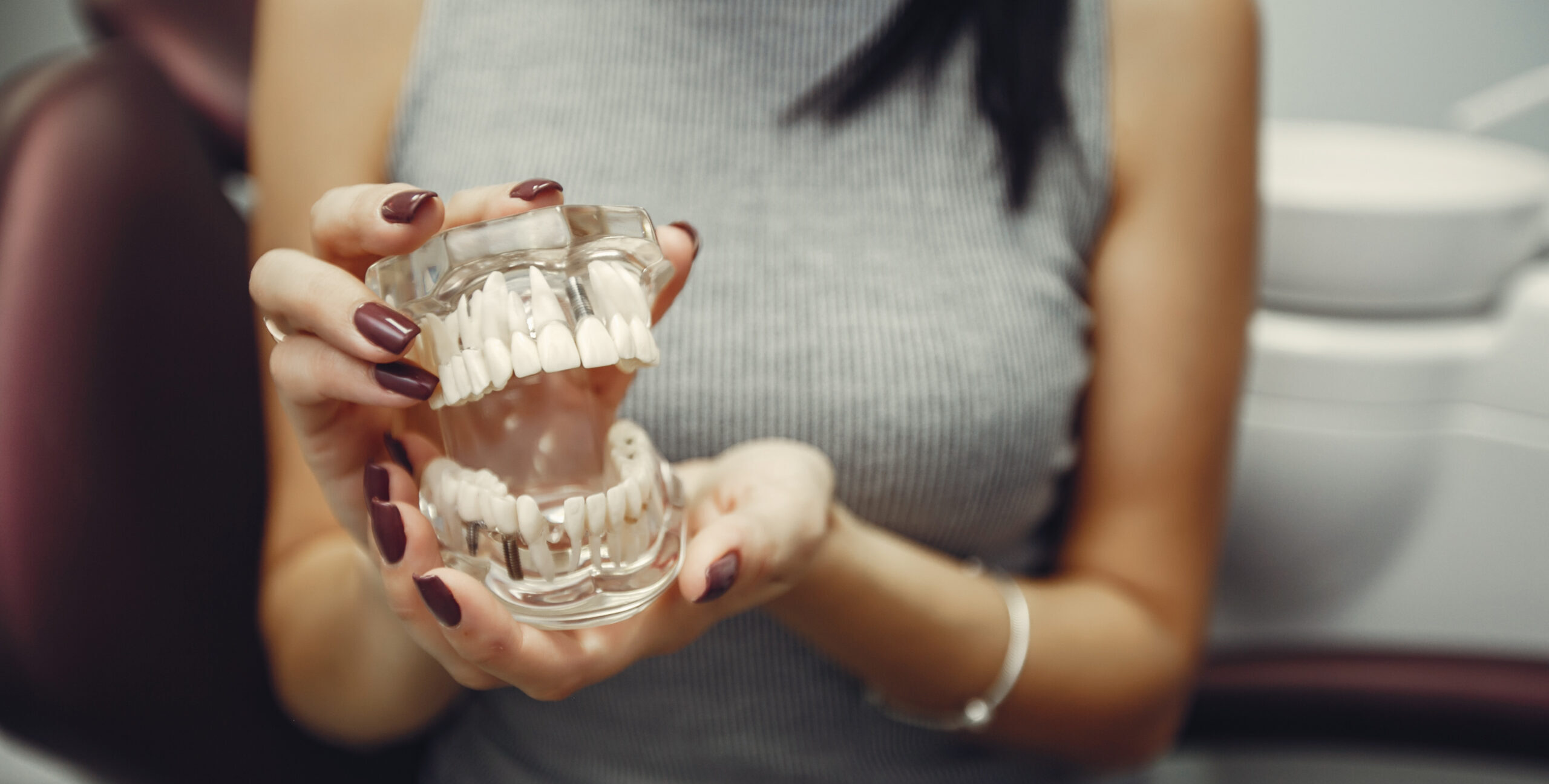 A dentist performing a dental implant procedure, placing a titanium post into the jawbone to replace a missing tooth.